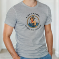 A man wearing light heather gray short-sleeve t-shirt with a vintage-style circular graphic on the chest. The graphic features a pin-up illustration of a woman in a red bikini  seated on a blue anchor, with the text 'LAKE ONTARIO' above and 'Resist the Rebrand' below in black.