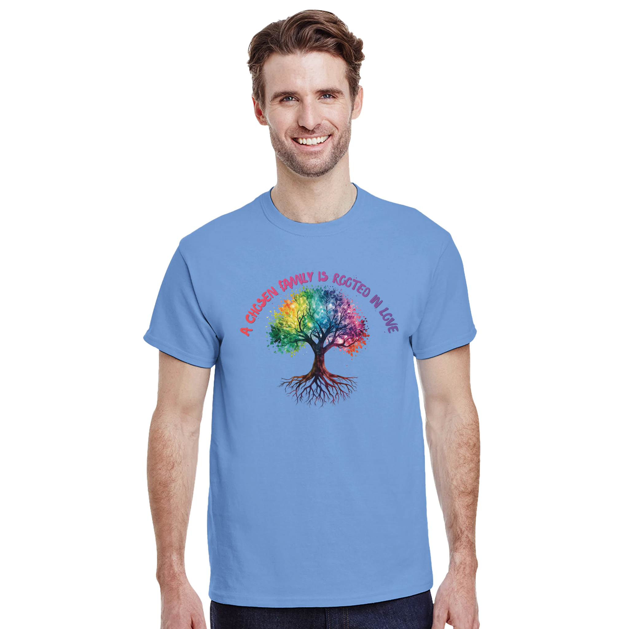 A man wearing a Carolina Blue t-shirt featuring a colorful graphic of a tree with a rainbow-colored canopy and roots, with the text 'A Chosen Family is Rooted in Love' arched above it in pink and purple lettering.
