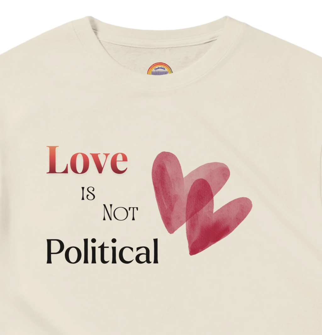 Natural Beige short-sleeve tee with a graphic print on the chest reading 'Love IS NOT Political' in black and red text, accompanied by two overlapping red hearts. 