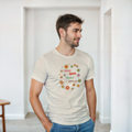 A natural beige tee with a graphic design featuring the text 'More queer than I appear' in a playful, retro font, surrounded by a circle of smiling, colorful flowers.