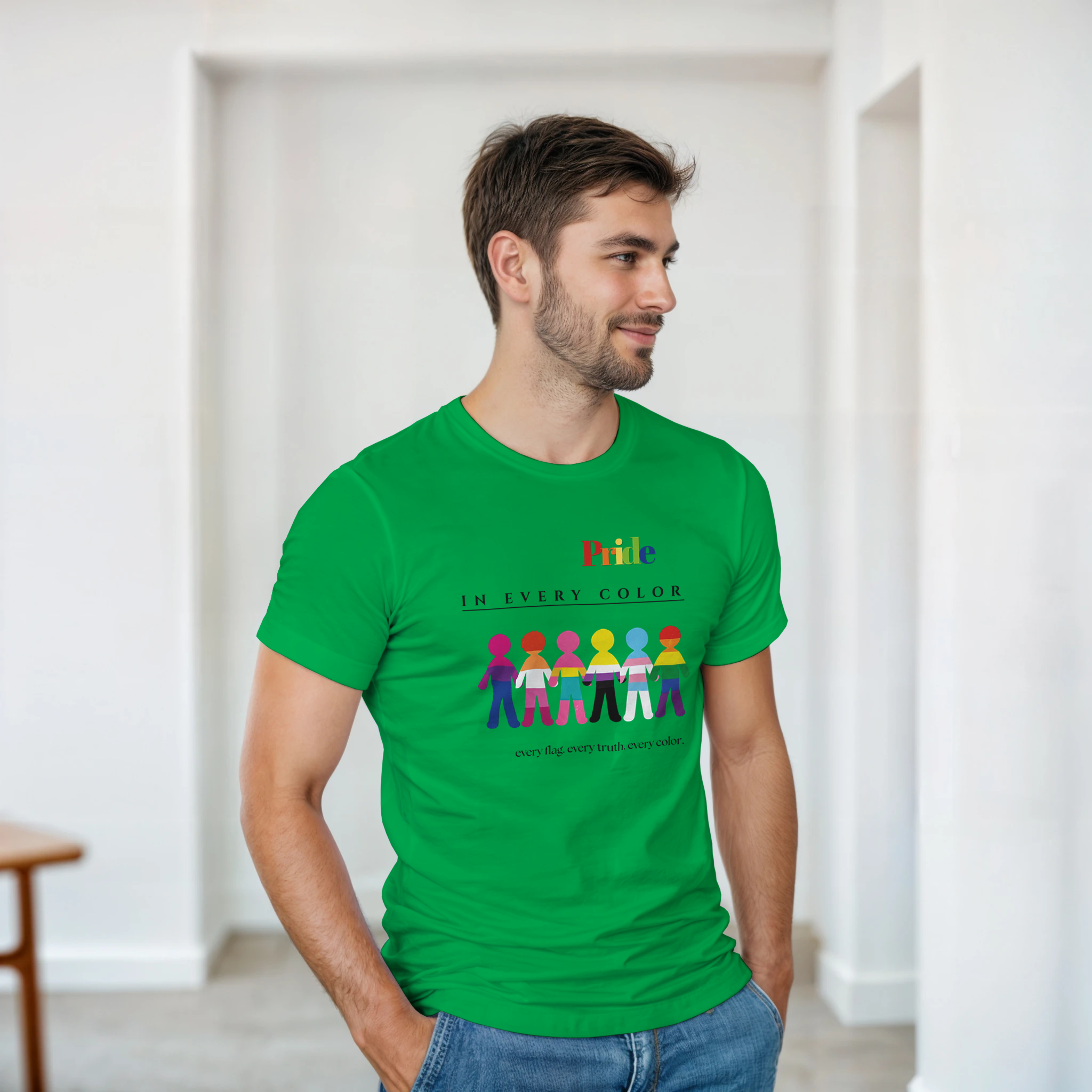 A man wearing an irish green tee with a message Pride in Every Color followed by design of paper doll chain, each in a different pride flags colors.  Underneath is the wording, 'every flag. every truth. every color.