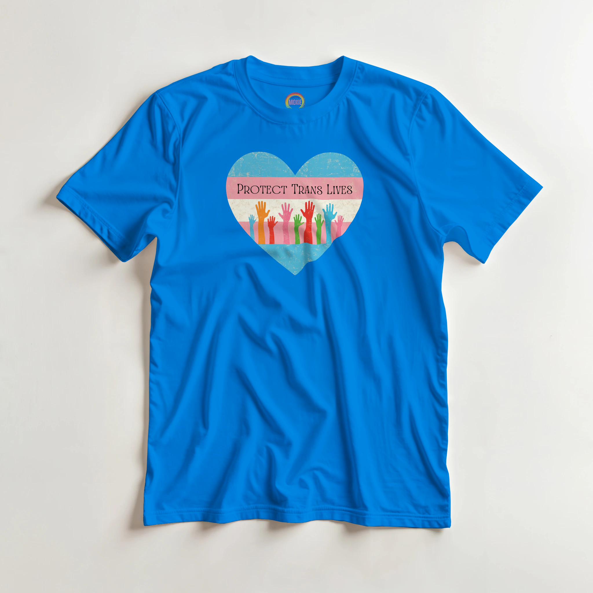 A graphic print on a royal blue garment featuring a distressed heart design with the text 'PROTECT TRANS LIVES' and colorful raised hands in a transgender pride flag color scheme.