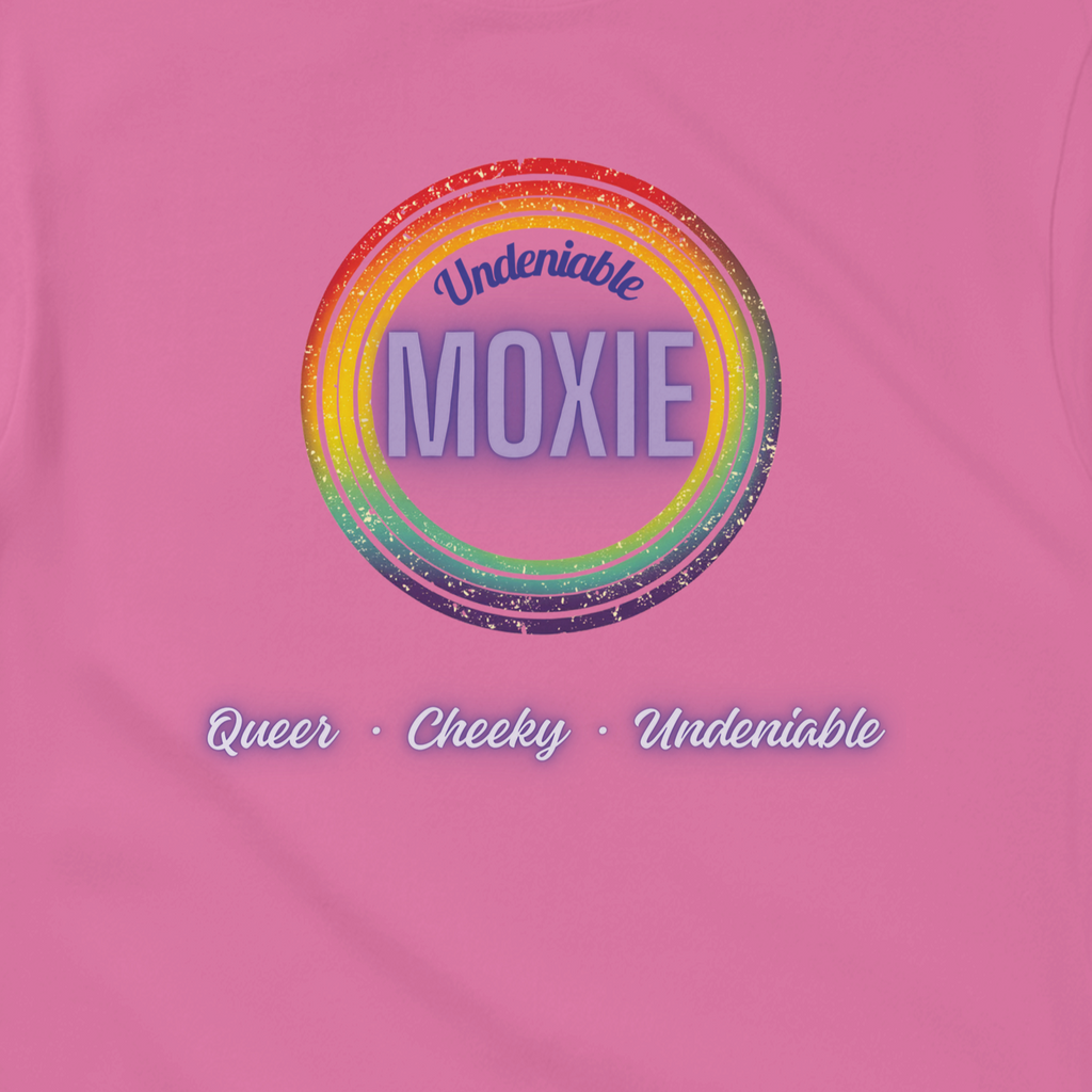 Graphic print on an azalea colored t-shirt featuring a circular rainbow design with the text 'Undeniable MOXIE' and 'Queer • Cheeky • Undeniable' written below in a stylized font.