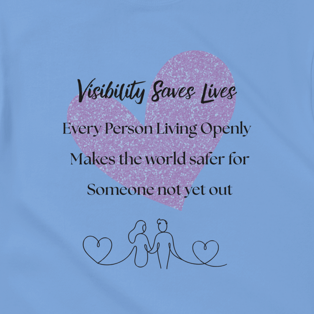 Carolina Blue shirt design with a watercolor-style graphic heart on the front. The shirt reads 'Visibility Saves Lives' and 'Every Person Living Openly Makes the world safer for Someone not yet out' with a line drawing graphic of 2 female presenting figures holding hands and hearts.
